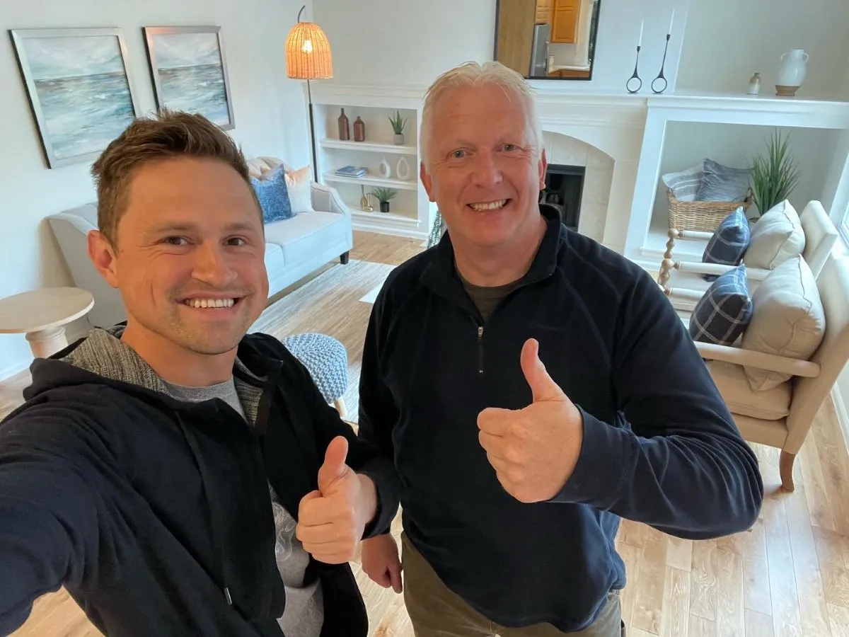 A Vision Flooring team member and a smiling homeowner giving a thumbs up in a living room