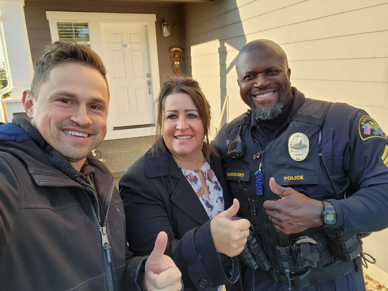 A Vision Flooring team member with two smiling homeowners giving a thumbs up outside a house