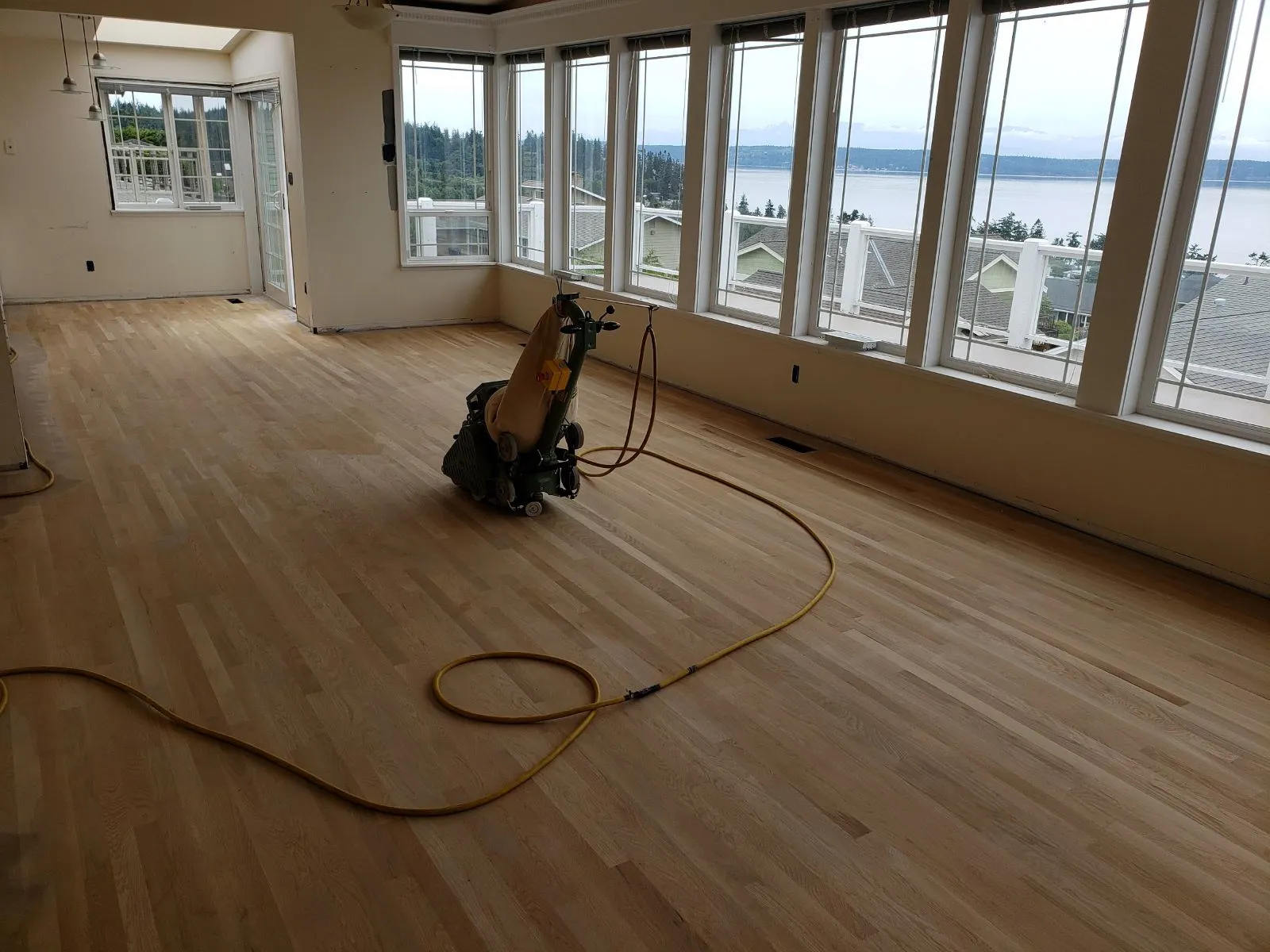 Hardwood floor being sanded in a room with water views