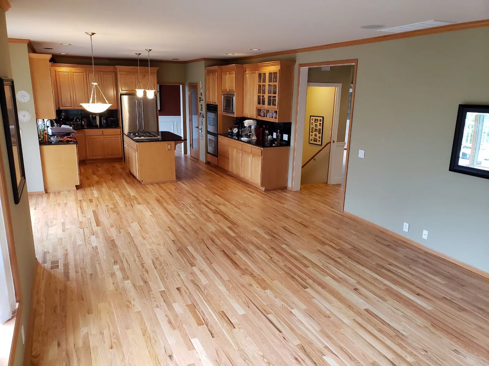 Light hardwood floor through an open living area and kitchen