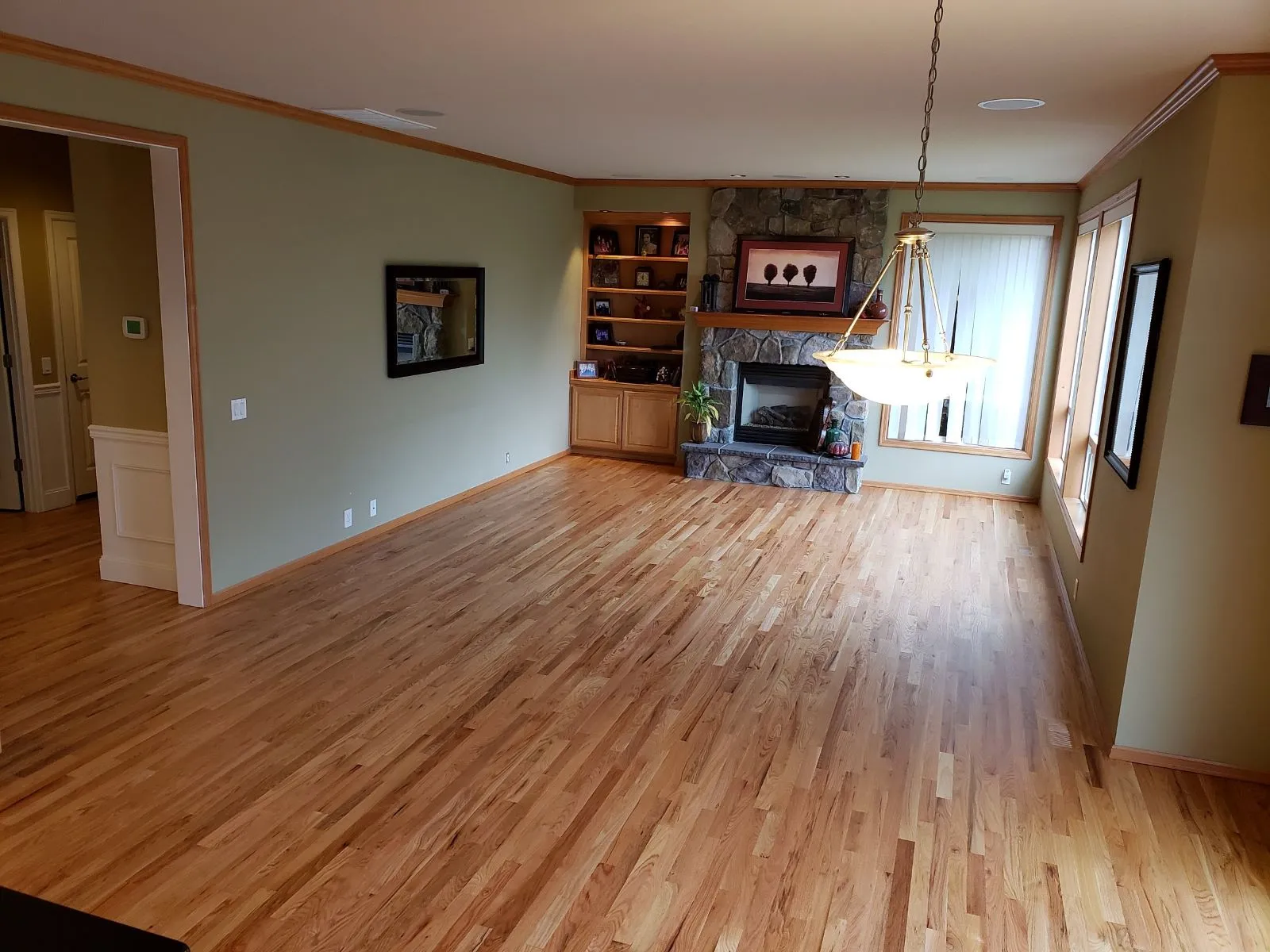 Refinished hardwood floor in a living room with a fireplace