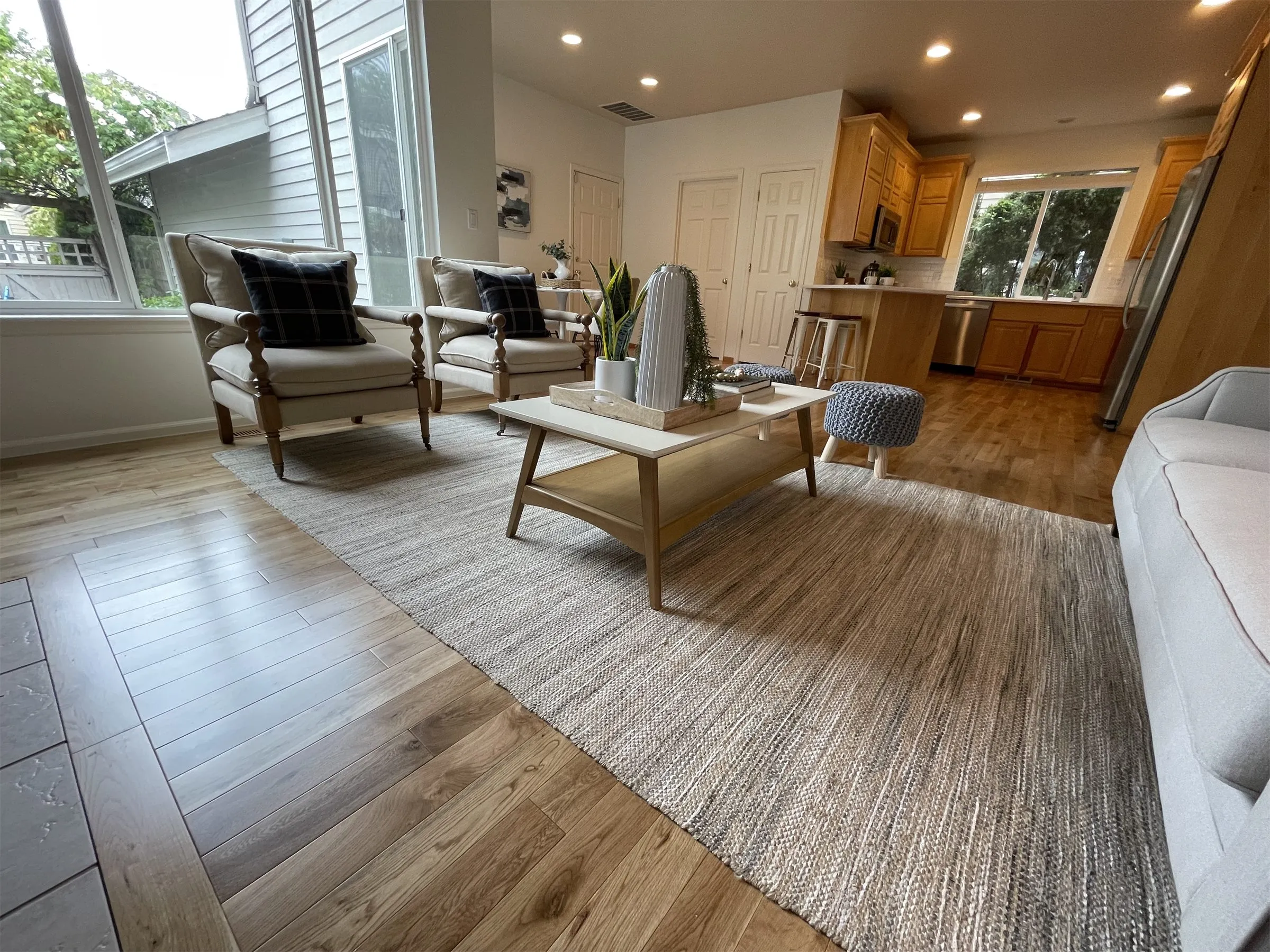 Bright living room with a light hardwood floor, a sofa and a kitchen in the background
