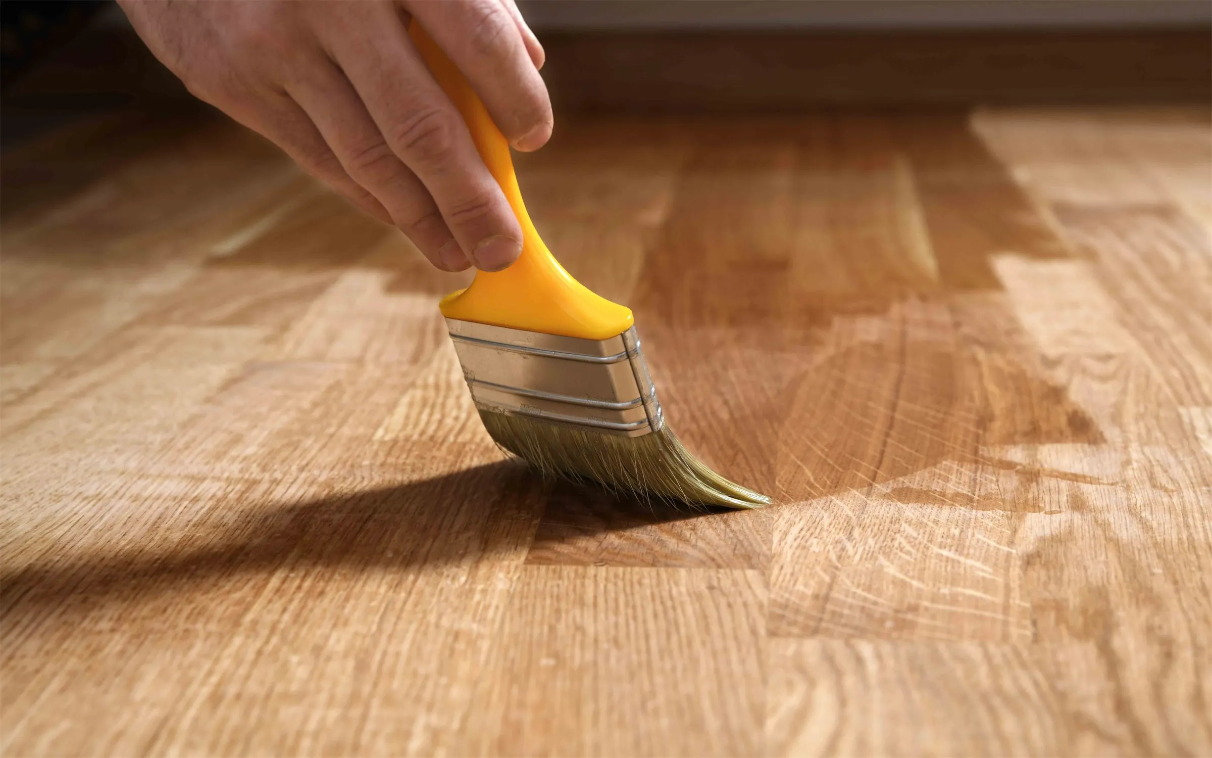 A hand brushing finish onto a wood floor