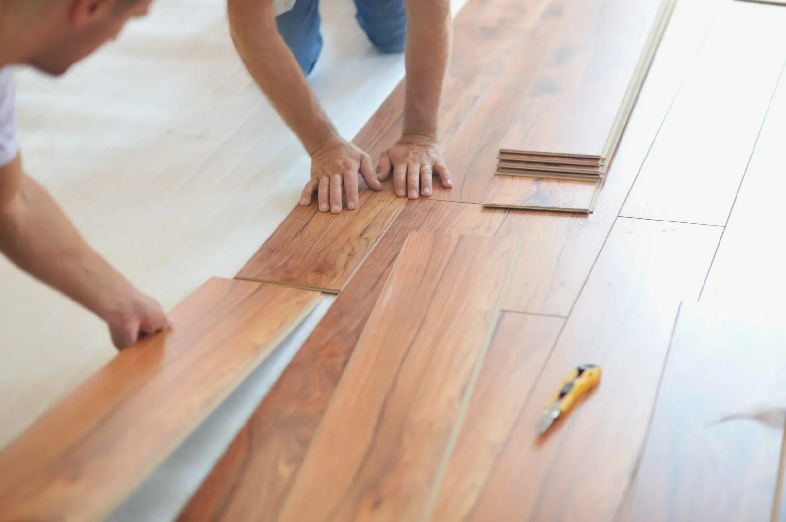 Hands clicking wood-look laminate planks together on a floor
