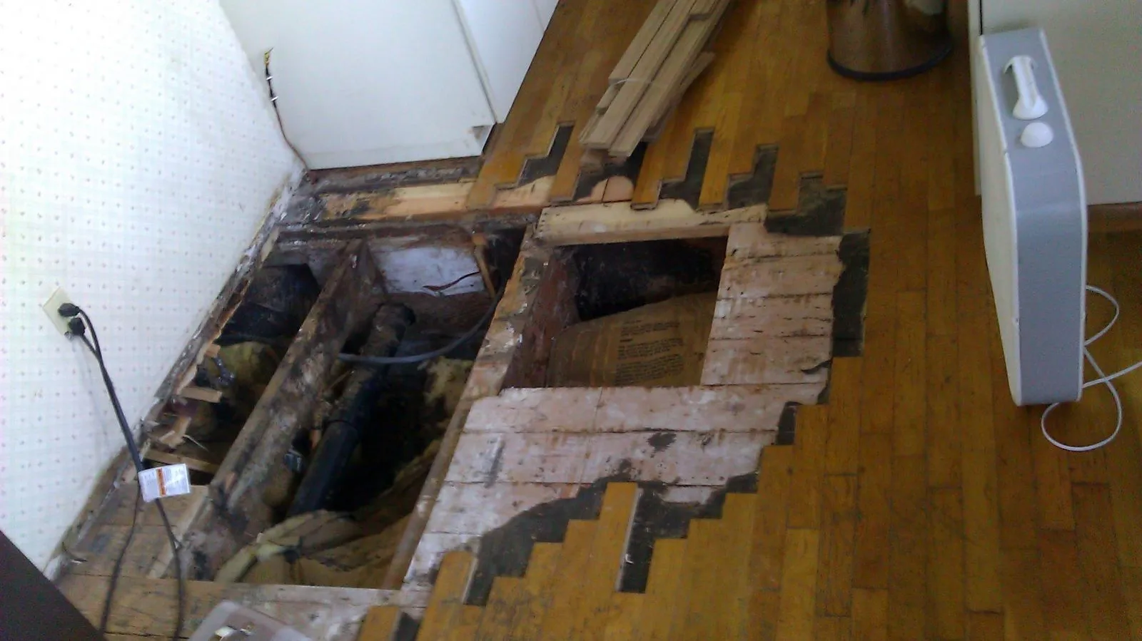 Damaged floor and subfloor boards cut out for repair